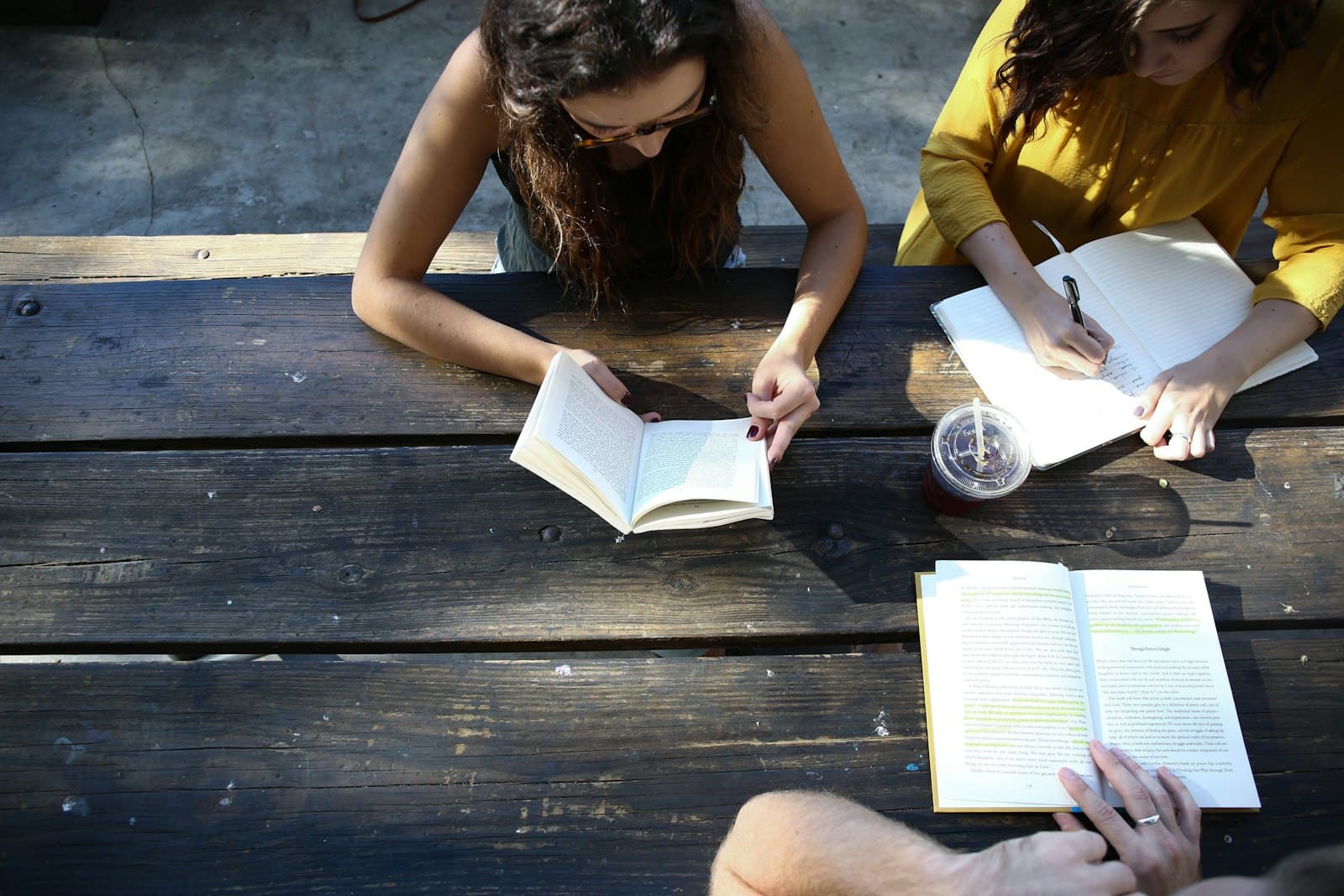 Two students reading and taking notes together at a wooden table